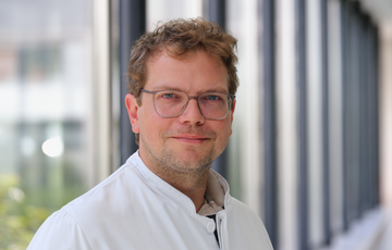 Dr. med. Daniel Schacht im Portrait im weißen Kittel