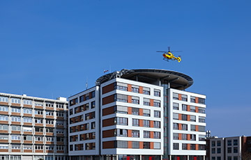 •	Das Rhein-Maas Klinikum mit Anbau in der Rückansicht. Ein gelber Hubschrauber vom ADAC landet auf dem Hubschrauberlandeplatz. 