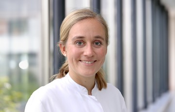 Maja Hüsing in weißem Kittel in einem Gang des Krankenhauses