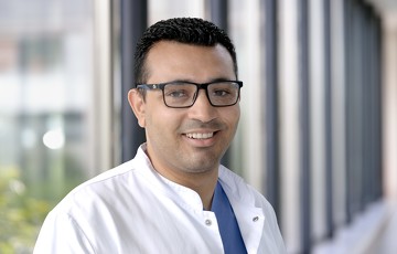 Ramez Markus in weißem Kittel in einem Gang des Krankenhauses