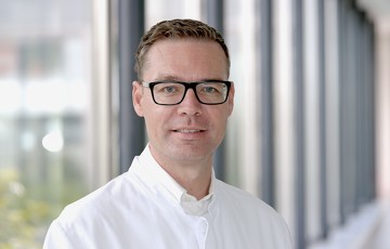 Stephan Schulte im weißen Kittel in einem Gang des Krankenhauses