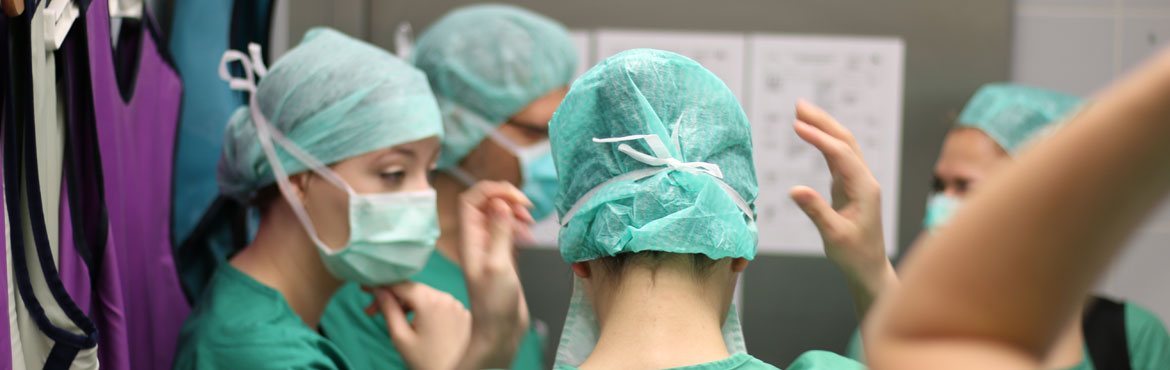 Vijf mensen kleden zich steriel voor een operatie